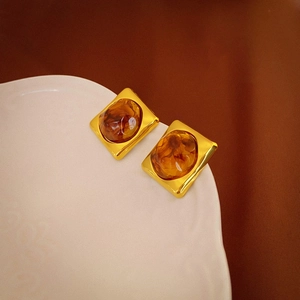 Macro detail of vintage gold-plated rectangular earrings with amber resin insets