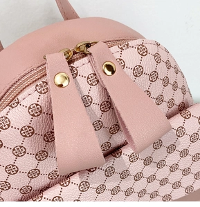 Close-up of pink litchi grain leather backpack with clover print and gold zippers