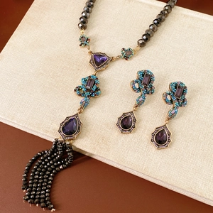 Détail du collier vintage en bronze avec strass violets et pompons en perles noires