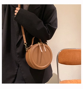 Piccola borsa rotonda vintage marrone indossata da modella in elegante blazer nero