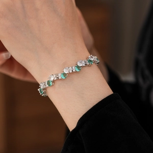Detailed macro view of silver zircon bracelet featuring emerald green round-cut gemstones