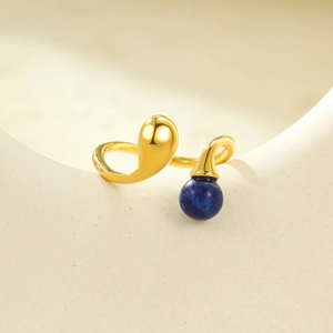 Bague ouverte dorée 18 carats avec pierre naturelle bleue sur fond neutre chic