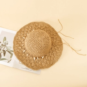 Detail of hand-woven straw hat featuring white shell accents and hollow knit pattern