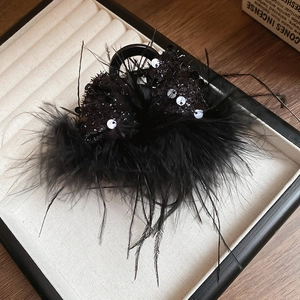 Macro shot of elegant black feather and sequin hair clip inside a jewelry box