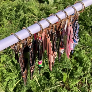 Various patterned PU leather keychain card holders hanging outdoors on a white rod