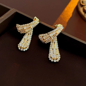 Détail macro de boucles d'oreilles dorées avec oxydes de zirconium et design ruban