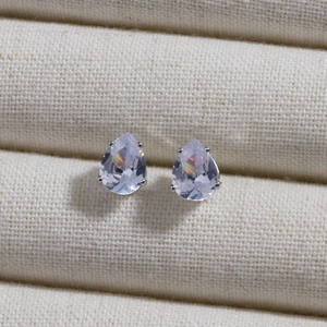 Macro shot of silver teardrop earrings with sparkling rainbow cubic zirconia on fabric