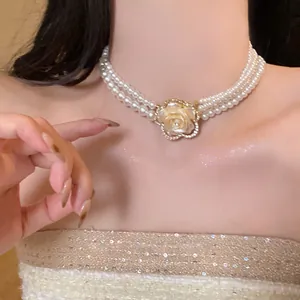 Detail showing triple-layer pearl necklace with a rhinestone flower pendant on model