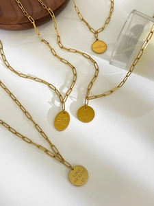 Detail of 18K gold paperclip chain necklace with engraved round and oval sun pendants