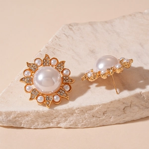 Detail of sunflower stud earring featuring faux pearls and crystals on textured stone