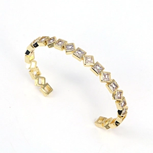 Detail of gold-plated open bangle featuring square-cut white zircon in bezel settings