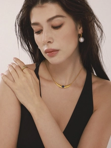 Detail of elegant gold moon necklace with blue stone and large pearl earrings set