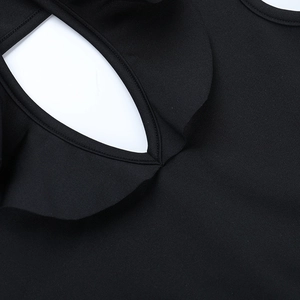 Detalle de escote en V con volantes y diseño calado en vestido negro de manga larga