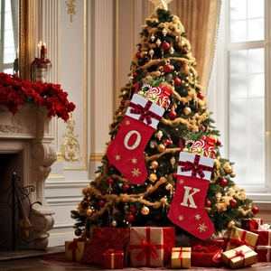Detail of red Christmas stockings with gold embroidery letters and plaid bows on a tree