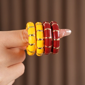 Detailed macro view of vintage enamel bangles in yellow and wine red with gold stripes