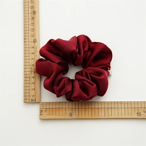Premium wine red satin scrunchie with metallic tag and elegant pleated texture