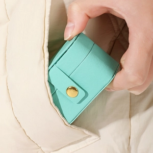 Mini travel jewelry box in mint green leather being tucked into a pocket for portability