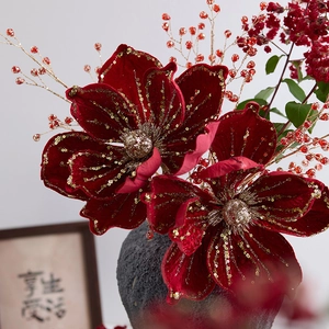 Artificial red velvet Christmas flowers with gold glitter in a ceramic vase decor