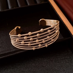 Detail of gold multi-layer beaded spiral cuff bracelet on a black velvet display base