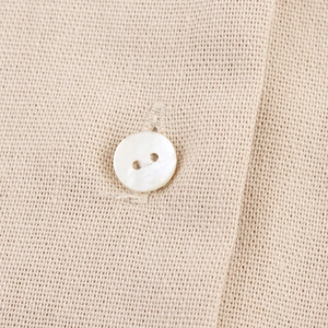 Close-up of beige linen V-neck blouse with lace patchwork and white button details