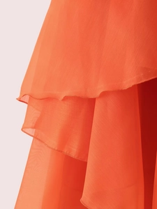 Détail en mousseline orange avec plis multicouches montrant une texture de volant exquise