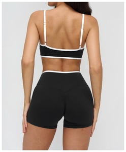 Rear view of black yoga set with white contrast trim on sports bra and high waist shorts