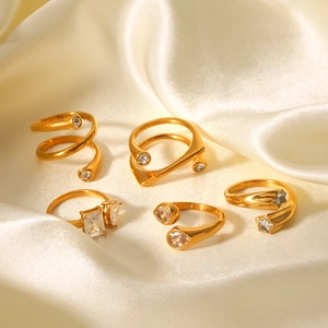 Set of five 18K gold plated rings with zircon stones on champagne silk fabric background