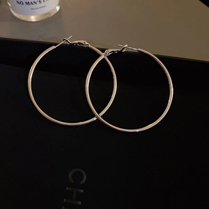 Macro shot of silver-tone large hoop earrings with high-polish finish on a black box