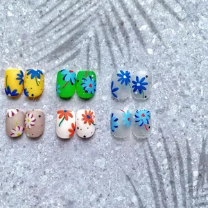Macro detail of daisy and sunflower patterns on assorted color press-on nails