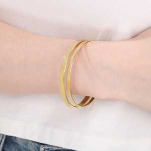 Close-up of double-layer 18k gold plated stainless steel bangles worn on a wrist
