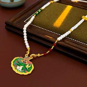 Macro shot of pearl necklace with gold Ruyi lock pendant and green enamel animal detail