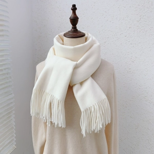 Detail shot of a white faux cashmere scarf with tassels on a model for winter style