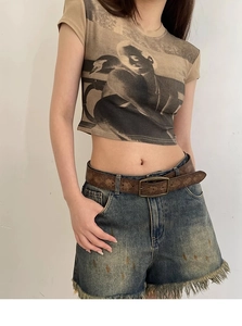 Detail of vintage embossed brown leather belt paired with denim shorts and y2k style top