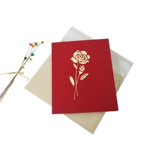Close-up of red 3D rose greeting card with golden cutout detail and beige envelope