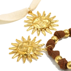 Detail shot of the golden sun face pendant with fine textures and woven bead cord