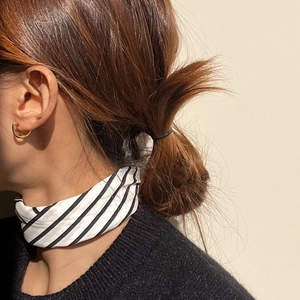 Minimalist oval gold stud earrings paired with black and white striped scarf on model