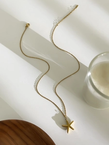 Détail d'un pendentif étoile de mer doré minimaliste sur une chaîne de collier fine