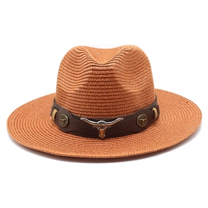 Straw cowboy hat with bull head emblem and brown leather strap on white background