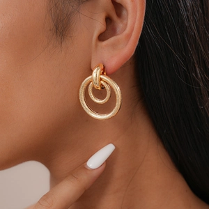 Macro detail of golden double hoop earrings with snake skin texture on the model