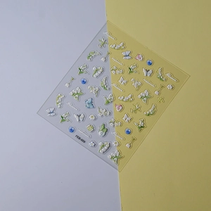 Detailed macro view of 3D embossed lily of the valley and butterfly nail art stickers