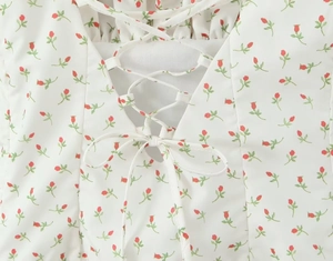 Close-up of white floral A-line dress featuring red prints and criss-cross back straps