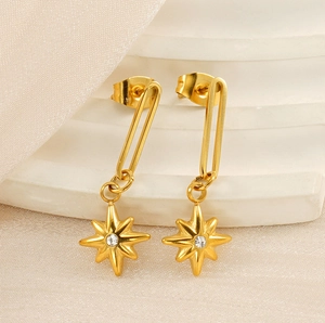Macro shot of 18K gold plated North Star drop earrings on white silk and stone
