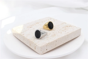 Polished gold and silver signet rings with black oval inlay on stone display base