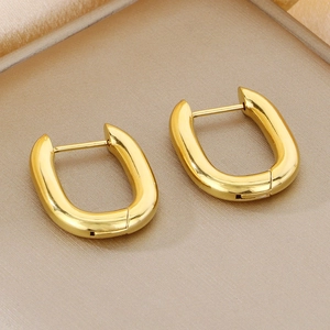 Detail view of gold U-shaped geometric earrings on a champagne gold brushed tray