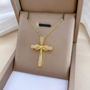 Dettaglio di una collana a croce intrecciata dorata con zirconi in un portagioie