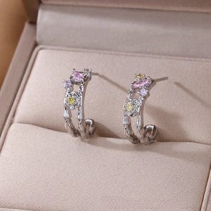 Macro shot of silver C-shape earrings with rose relief and pink marquise stones