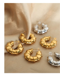 Detailed close-up of gold and silver croissant-style earrings on premium silk fabric