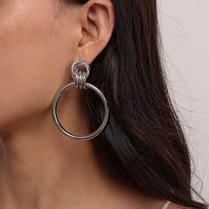 Close-up of minimalist silver geometric double hoop earrings worn by a female model