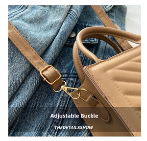 Detail of adjustable shoulder strap with gold metal buckle on beige quilted handbag