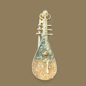 Détail de la pince à cheveux pipa avec rose dorée, perles et résine bleue incrustée